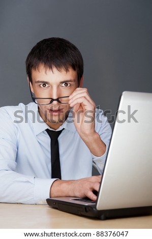 Portrait of a adult excited business man sitting by his laptop in the office and looking at camera expecting something