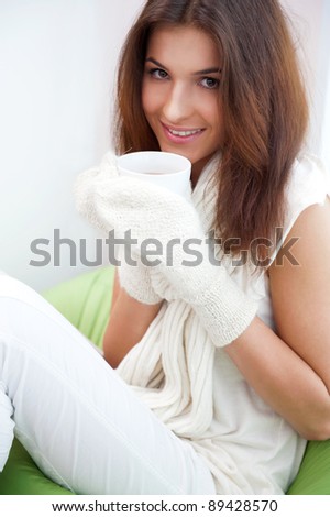 Day dreaming - Caucasian American female relaxed at home, having a cup of tea. Wearing wool scarf and gloves. Flu prophylaxis concept