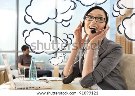 Portrait of a beautiful young businesswoman on the phone and happy. Office background. Blank dialog cloud balloons around her