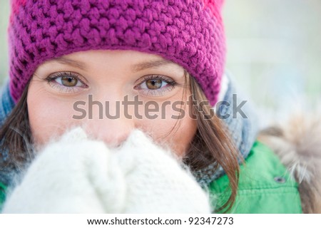Winter woman in snow looking at camera outside on snowing cold winter day. Portrait Caucasian female model outside in first snow