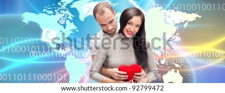 Portrait of young couple embracing and holding red heart. Standing against world map. International dating concept