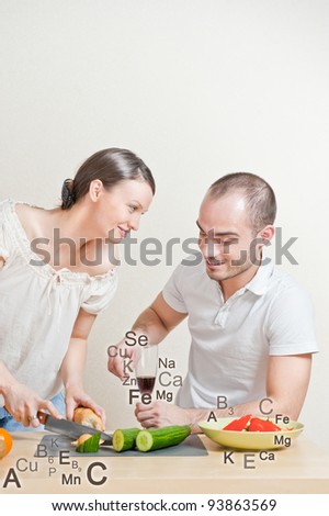 Young lovely couple cooking a balanced diet. Big copyspace. Vitamins and microelements symbols are around them.