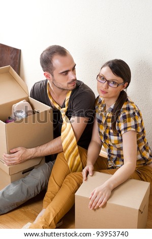 Young Couple with boxes in the new apartment sitting on floor and planning their future, dreaming about something positive