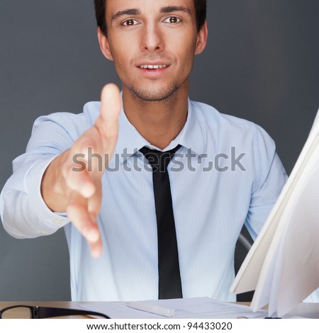 Portrait of an adult business man sitting in the office and holding contract and giving handshake