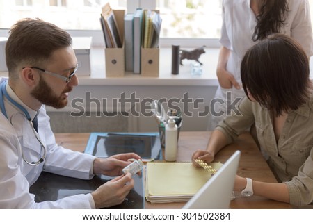 At doctor office. Doctor talking to patient after tests. Nurse standing near patient