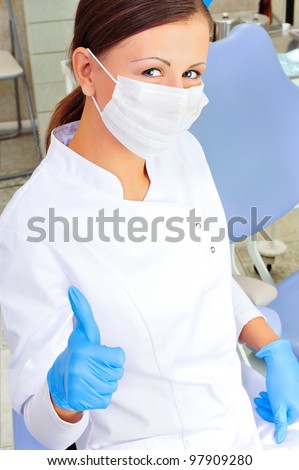 Woman dentist at her office smiling wearing formal medical suit and thumbs up