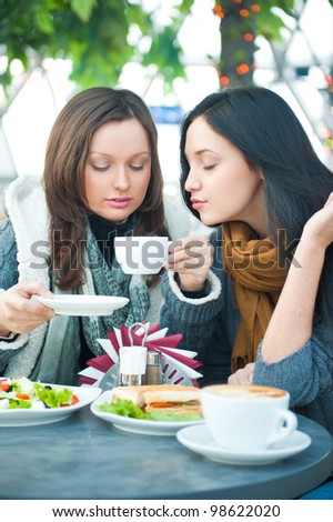 Two beautiful women having lunch and chatting at cafe