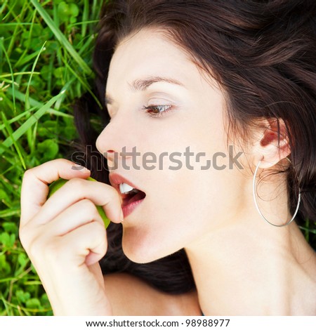 Pretty brunette girl wearing elegant dress relaxing outdoor in green grass and smells aromatic lemon or lime citrus