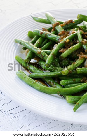 Green string beans chinese dish with spices. Green beans fried with onion, soy sauce, garlic and spices.