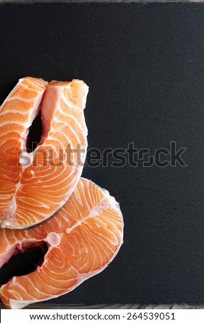 Fresh salmon steak on black stone. Healthy food, diet or cooking concept.