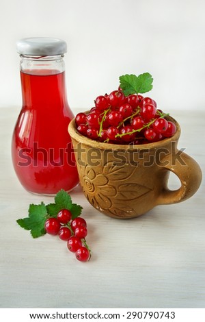 red currants in a clay cup and a bottle of juice