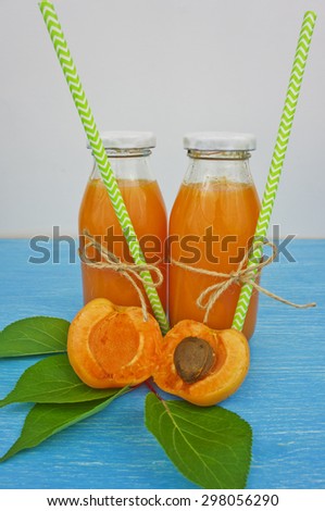 apricot juice in bottles with straws on a wooden table