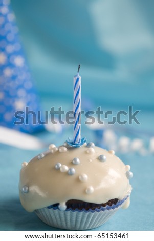 Birthday muffin with blue candle on blue background