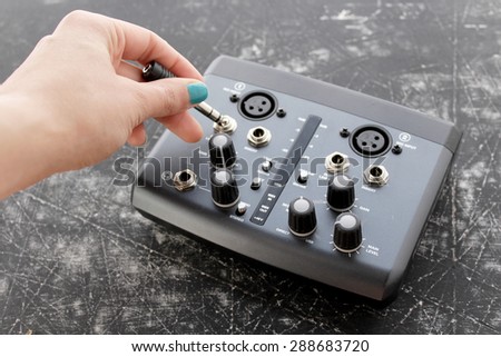 Audio interface for recording or mixing - sound/audio card, and woman's hand holding amplifier