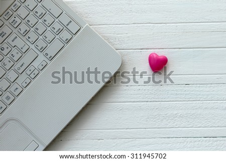 Lap top computer and heart on wooden white table - love technology concept
