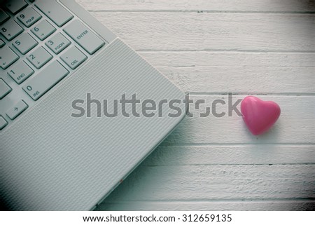 Lap top computer and heart on wooden white table - love technology concept - vintage effect