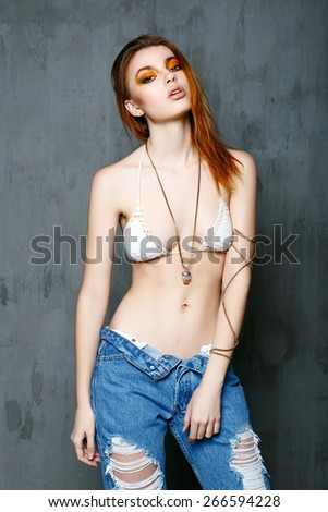 Fashionable beautiful woman in jeans on gray background