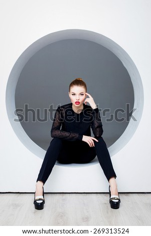 Sexy woman posing in circle hole in wall
