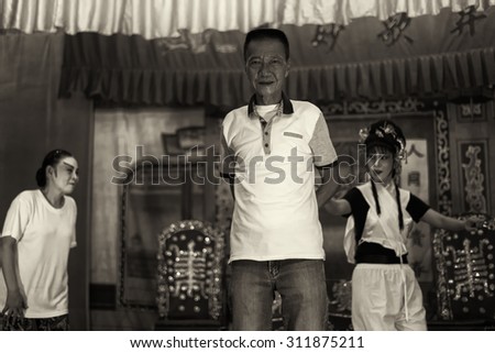 SINGAPORE - AUG 20: Dark sepia version of the opera troupe owner standing with opera singers rehearsing in the background on Aug 20, 2015 in SINGAPORE.