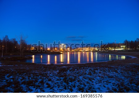 Evening lights reflection in city lake in winter evening, Russia