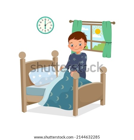 cute little boy making bed arranging pillow and bed cover neat doing his housework chores in the morning at home