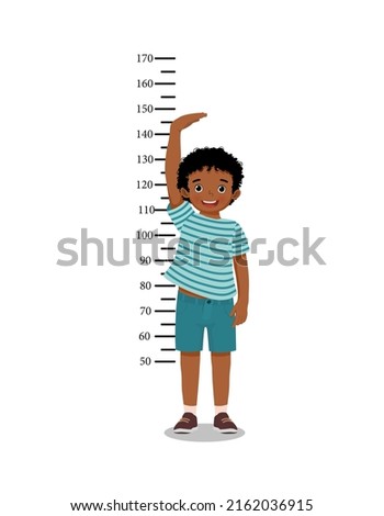 Cute little African boy measuring height of his growth on the background of wall