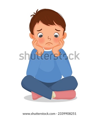 Sad little boy sitting on the floor with his chin resting on his hands