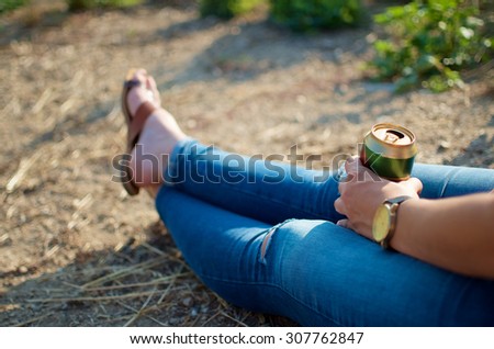 Girl sitting on the ground with can of beer
