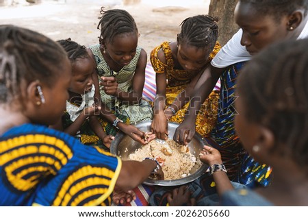 Group of African girls sitting around a big plate with rice and vegetables, enjoying their meal Imagine de stoc © 
