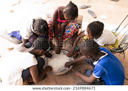 Group of African village children sharing a simple rice meal; concept of scarcity of food and malnutrition in developing countries Imagine de stoc © 