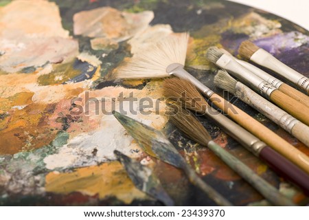 Paintbrushes laying on an old used palette with colors all over
