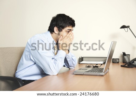 Businessman looking at his laptop computer screen as if faced with a big problem