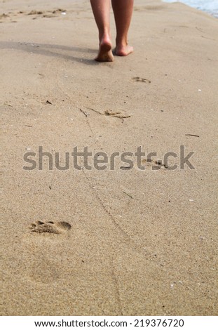 woman walking on sand beach leaving footprints in the sand