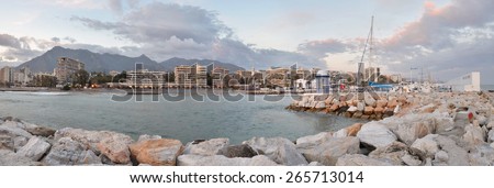 The panorama Marbella city seen from the port, coastal mountain range and cloudy sky are at background, sailing yacht club is at right Costa del Sol, Andalusia, Spain