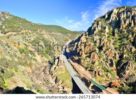 Highway and railway are crossing Sierra Morrena Mountains of Despenaperros Natural Park, following the river course in canyon. Los Organos geological formations are the natural monument at right.