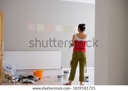 Rear view shot of a woman looking at color samples painted on wall indoors with copy space.
