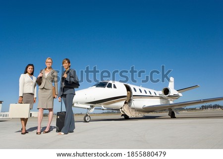 Low angle view of businesswomen standing in front of a private jet on the runway.