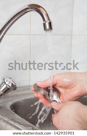 woman hands rinsing cutlery under running water in the sink