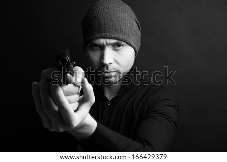 Portrait of a man holding gun against a black background