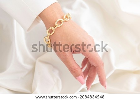 hand wearing a big gold chain bracelet and a white jacket Foto stock © 