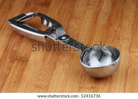 Ice cream serving spoon on wooden table.
