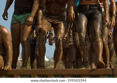 Group of people jumping over an obstacle during the Inferno run mud race