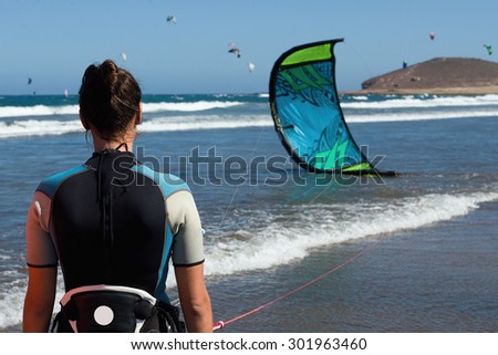 A young woman kitesurfer ready for kite surfing rides in blue sea
