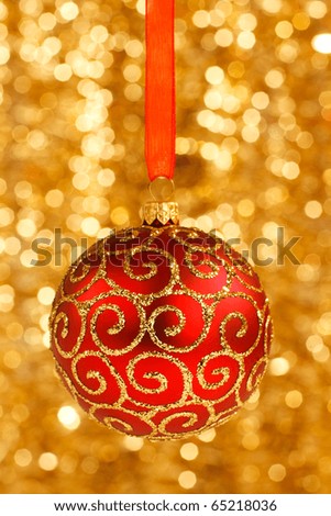 Red Christmas bauble on blurred golden background