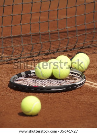 tennis racket with balls on clay court near the net