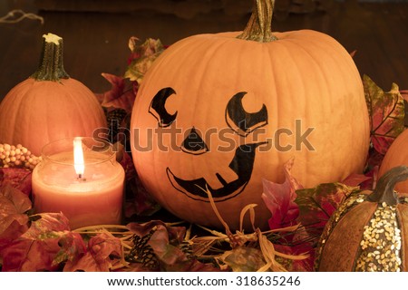 Painted Pumpkin face with sugar pumpkins and a lit candle for a Halloween decoration set up