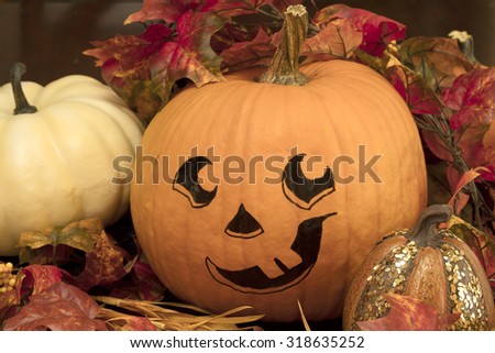 Painted Pumpkin face with sugar pumpkins and a lit candle for a Halloween decoration set up