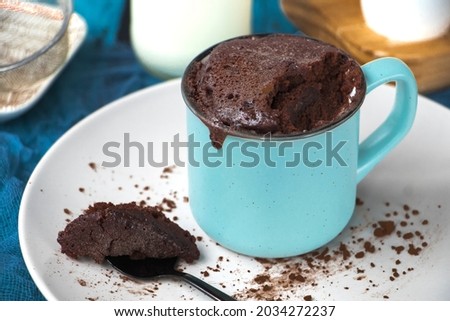 mugcake is microwaved. Homemade cupcake in a mug is on a plate. Chocolate brownie mug cake. Easy cooking concept, microwave baking. muffin chocolate. ingredients, eggs, milk, cocoa.