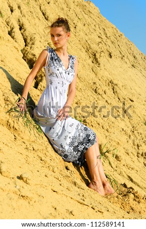 Beautiful woman in long dress posing at the sand place.