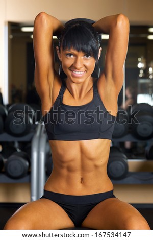 Beautiful woman is doing exercises at the gym in the sport club.